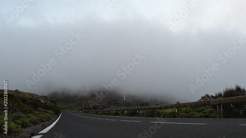 Asphalt road through Teide National Park with fast-moving clouds crossing the road