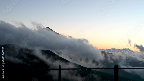 Cinematic close-up of Teide peak above clouds with glowing sunset sky