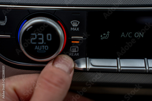 Tableau sur toile Close up of a finger pressing the rear window defogger button on a modern car dashboard console, activating the heating element for visibility and safety during cold weather