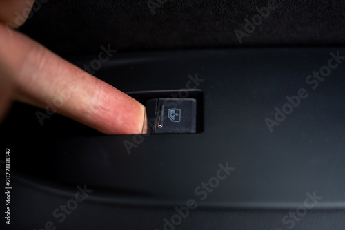 Foto Close up of a finger pressing an electric power window switch on a car door panel, demonstrating the use of automotive interior controls and convenience features