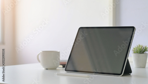 Tablet on desk with coffee cup.