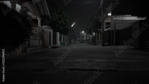 Shot in D-Log M Quiet empty suburban street at night in monochrome black and white with dim streetlights glowing in the darkness