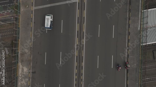 Aerial top down view of a highway bridge with moving motorcycles and a white minivan