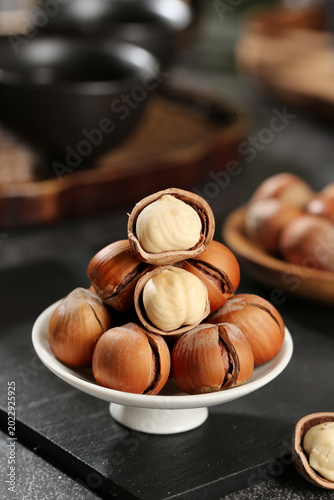Obraz na plátně Fresh Hazelnuts Cracked Open Showing White Kernels on Ceramic Stand