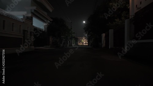 Quiet empty suburban street at night under a bright full moon with residential houses