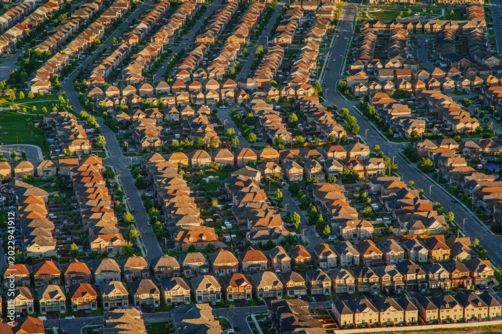 Fototapeta premium Aerial view of a suburban neighborhood with rows of houses at sunset.