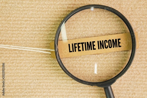 Фотография A magnifying glass and a paper tag with the words lifetime income