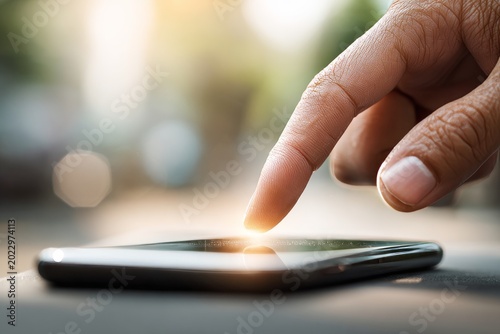 Close-up View of Hand Touching Smartphone Screen Outdoors in Sunlight