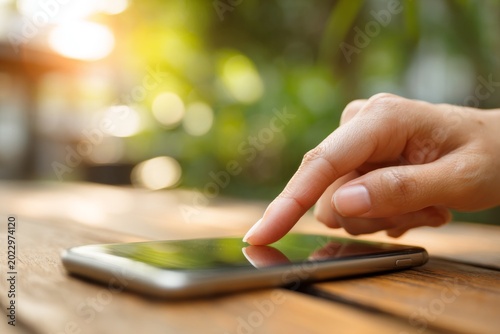 Close-Up Hand Touching Smartphone Screen on a Wooden Table Outdoors