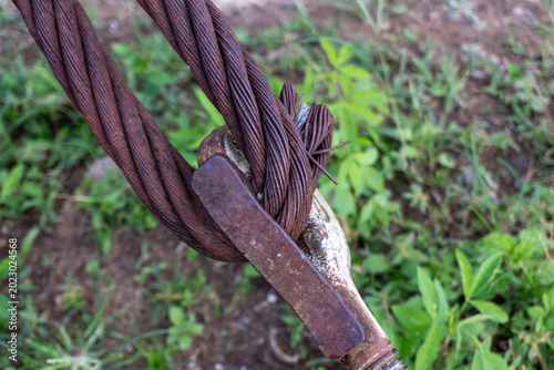 Close up of thick rusty steel wire rope cable and metal hardware over grass