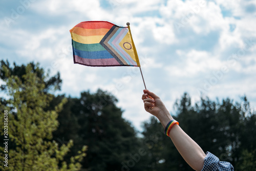 Photos Hand holding intersex inclusive progress pride flag waves against cloudy sky