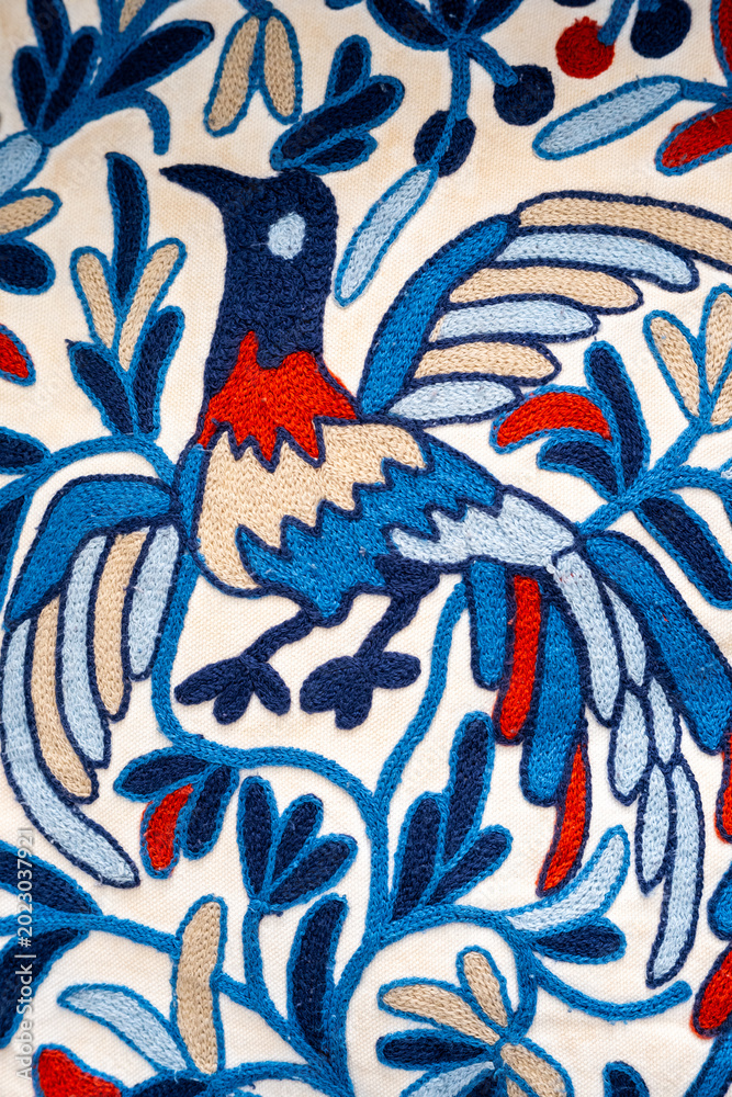 Obraz premium Artistic textile pattern featuring decorative bird illustration combined with floral ornamental motifs in blue, red, and white tones. Ideal for fabric design, wallpaper, decorative prints.