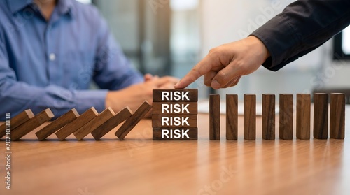 Hand stopping a falling tower of wooden risk mitigation blocks