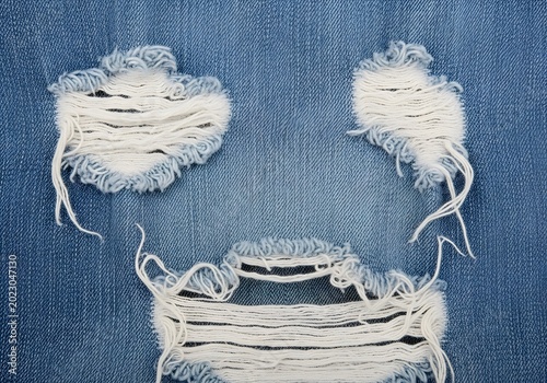 Close-up of ripped blue denim fabric revealing white threads and frayed edges in a casual fashion detail.