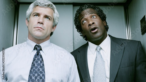 two businessmen in elevator looking confused and surprised at work
