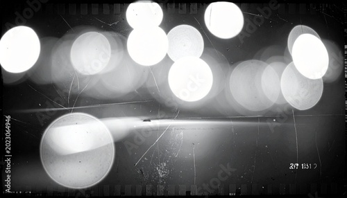 Cinematic black and white image of glowing bokeh lights on a dark textured background with scratches