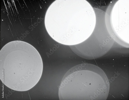 Glowing white bokeh lights on a dark textured background with scratches