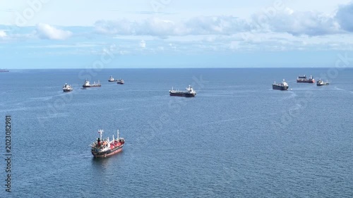 fast patrol boat with LPG gas and oil tanker ships anchored in the ocean, with a fast patrol boat in the foreground. Global energy transport, war energy crisis, and Strait of Hormuz blockade concept.