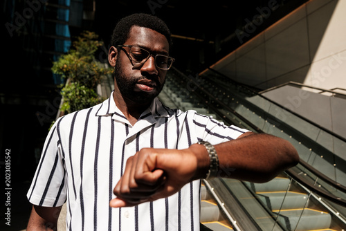 Black man checking wrist watch, managing time