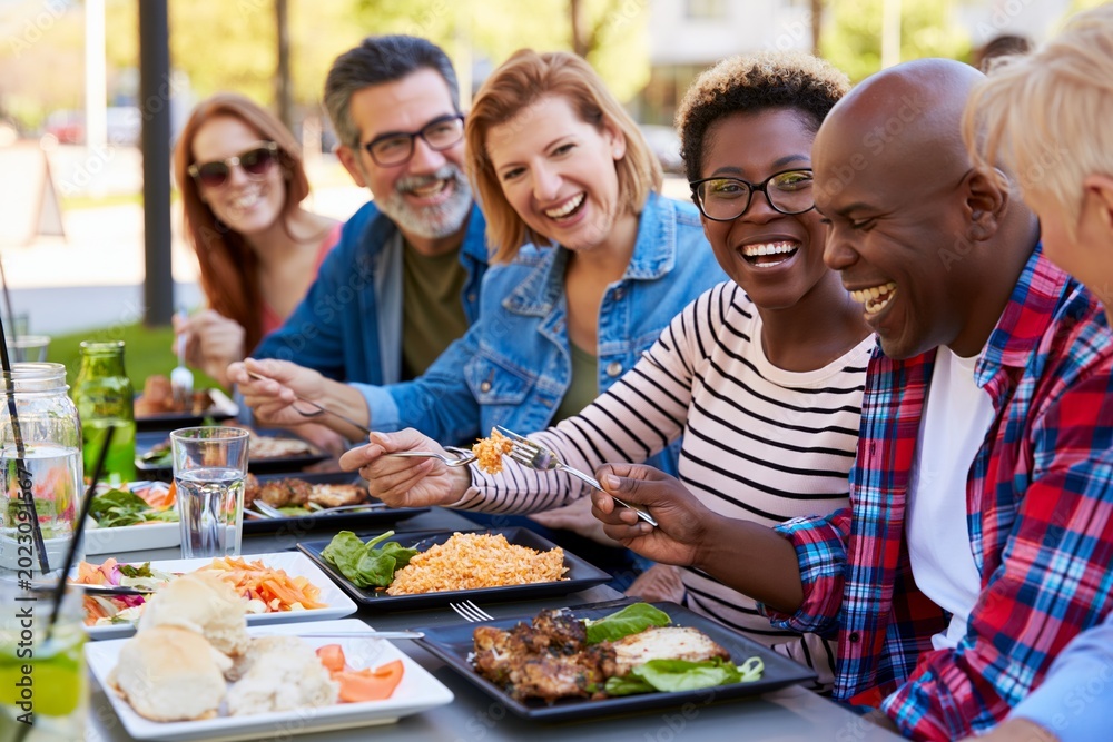 Obraz premium Happy group of friends eating together at outdoor cafe