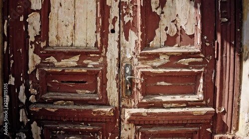 Front facing shot of a vintage wooden door with heavily peeling paint, showing layers of brown and beige tones