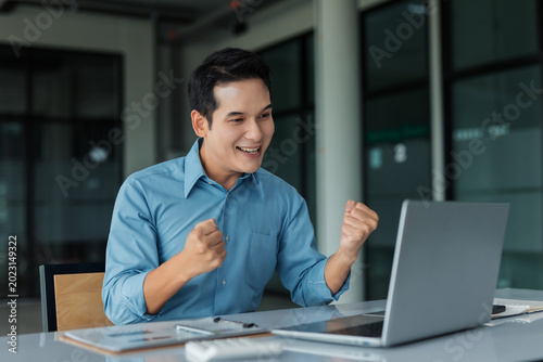Φωτογραφία Happy business man cheering, achieving goals, and feeling victorious while worki