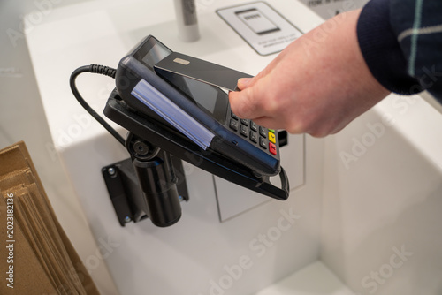 Foto Customer using credit card blip for NFC payment at store, cashless, contactless