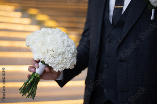 Tablou pe pânză wedding bouquet of delicate white carnations in the hands of the groom