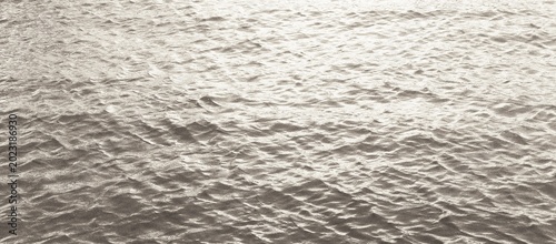 Fotografi Minimalist photograph of shimmering water with gentle ripples and bright reflections