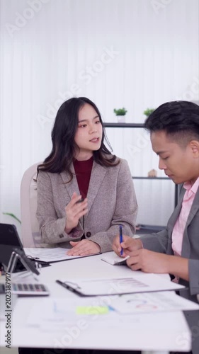 Asian business professionals consulting financial documents advisor explaining contract details client signing agreement modern office meeting workplace