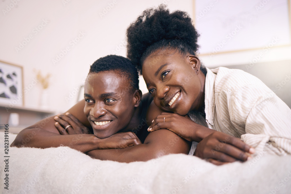 Obraz premium Couple, thinking and hug on bed in house, relationship or bonding with partner on break and romance. Black people, home and comfortable with spouse on weekend, happy and chill together with affection