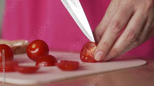 A housewife slices tomatoes to make sandwiches. Delicious breakfast at home.