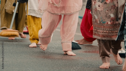 Crowd of Indian religious women clean the road for the Sikh guru