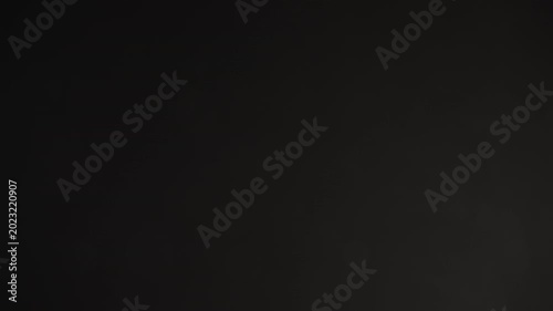 Slow motion real dust particles floating mid air over dark background