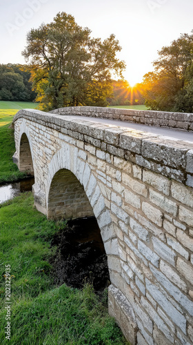 Historic stone bridge at sunset over green meadow