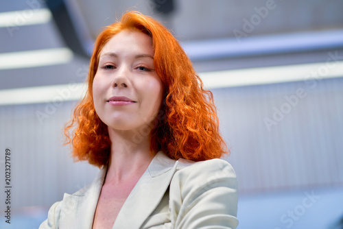 Businesswoman look at you for portrait in light color suit in co-working space office.