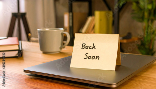 Back soon note placed on laptop on office desk