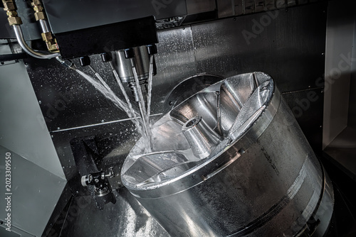 Foto CNC milling machine machining metal impeller with coolant spray.