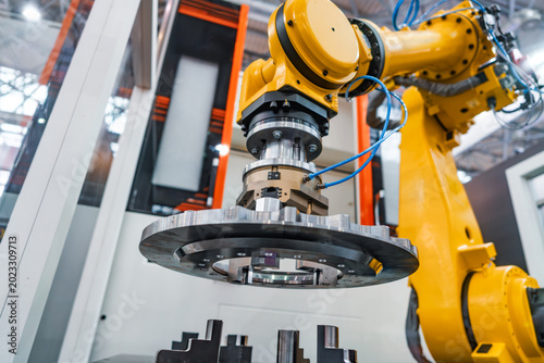 Canvas Print Industrial robotic arm holding metal gear component in automated factory cell