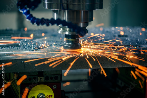 CNC milling cutter cutting metal with bright sparks in factory.