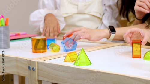 Fotografie Teacher and Students Interacting with Colorful Geometric Shapes on Light Table