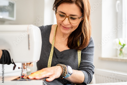 Tableau sur toile Woman Sewing At Home On A Sewing Machine