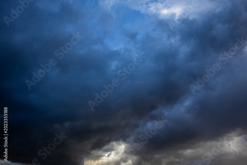 Fotografie Dramatic dark storm clouds filling the sky with brooding blue-grey tones and gli