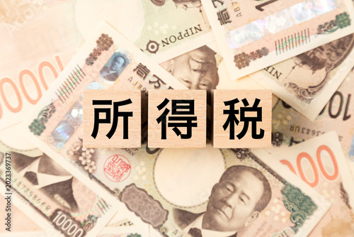 「所得税」と書かれたブロックとたくさんの一万円札