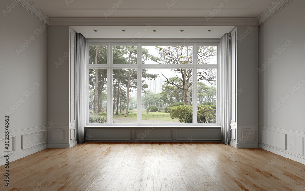 Fototapeta premium An empty room with a large window framing a park. Neutral palette, wood flooring, and classic trim create a calm, minimalist space
