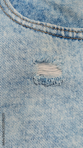 Close-up of stonewashed denim jeans with hole