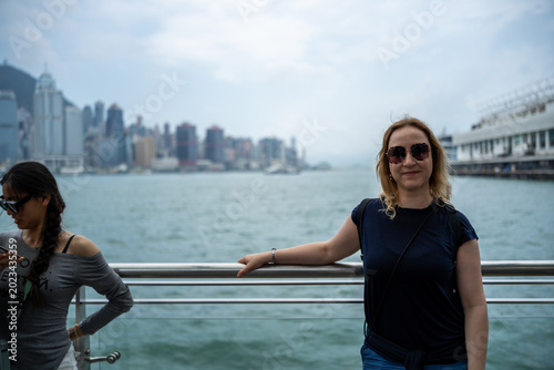 Two women enjoying a scenic view of Hong Kong's skyline from a waterfront promenade