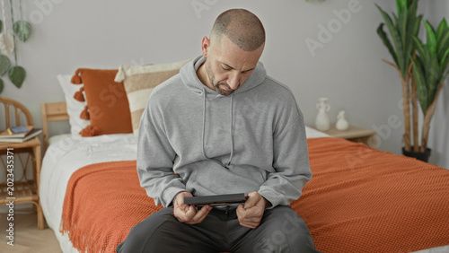 Photography Man holds frame to chest while seated on bed in studio room, hands clasped over keepsake and smartwatch visible; grief memory