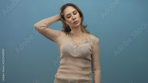 Fotografie Woman hand on head shrugging with other palm up wearing beige sweater in studio; annoyance resignation indifference