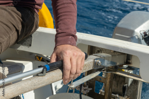 a man's hand resting on the steering wheel of a motor yacht